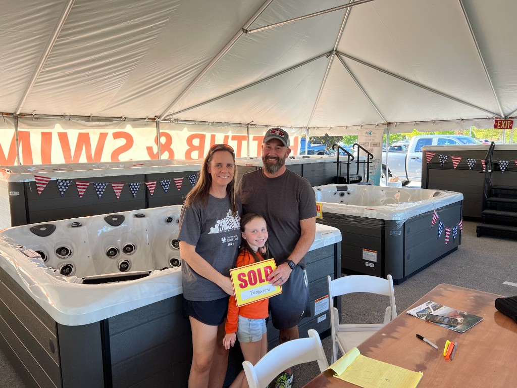 Family with a sold sign next to their new hot tub at the expo
